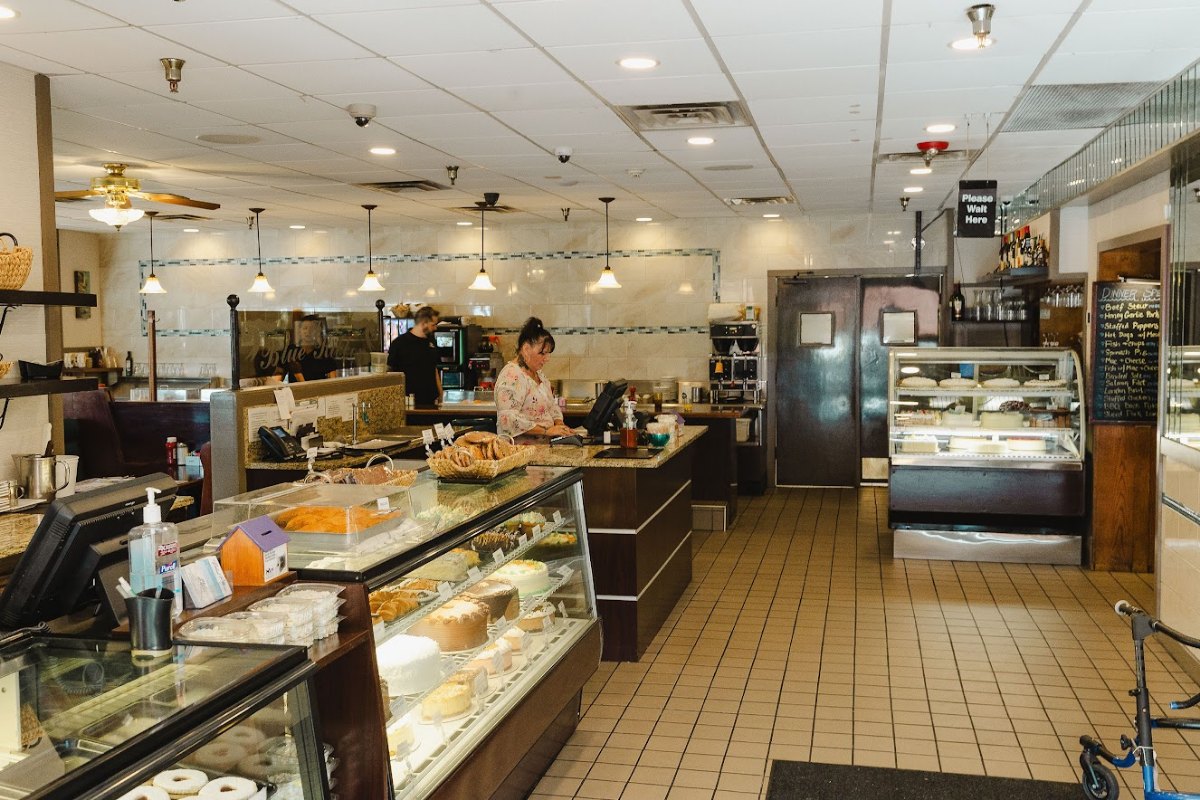 Part of the interior of the restaurant near the cash register and display case with desserts